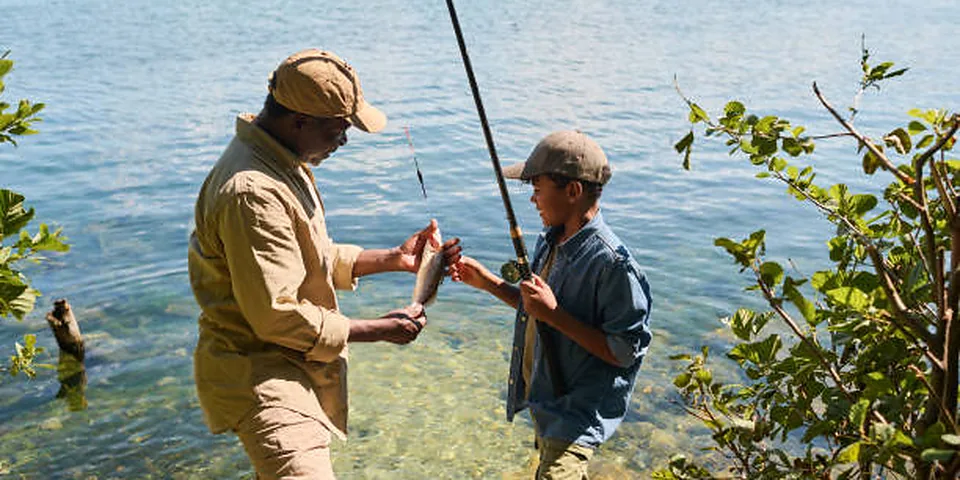 Fishing rod beside a clear rocky stream with natural forest shoreline