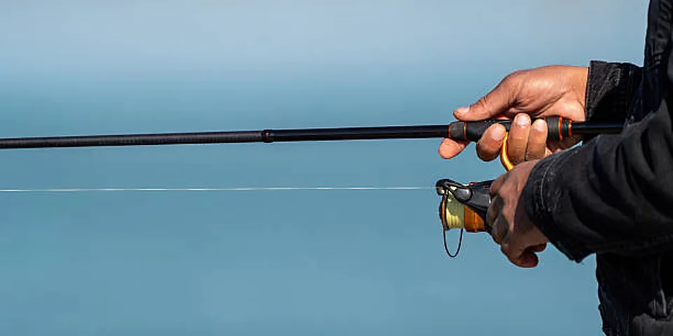 Two different sized fishing rods on an empty dock beside calm water