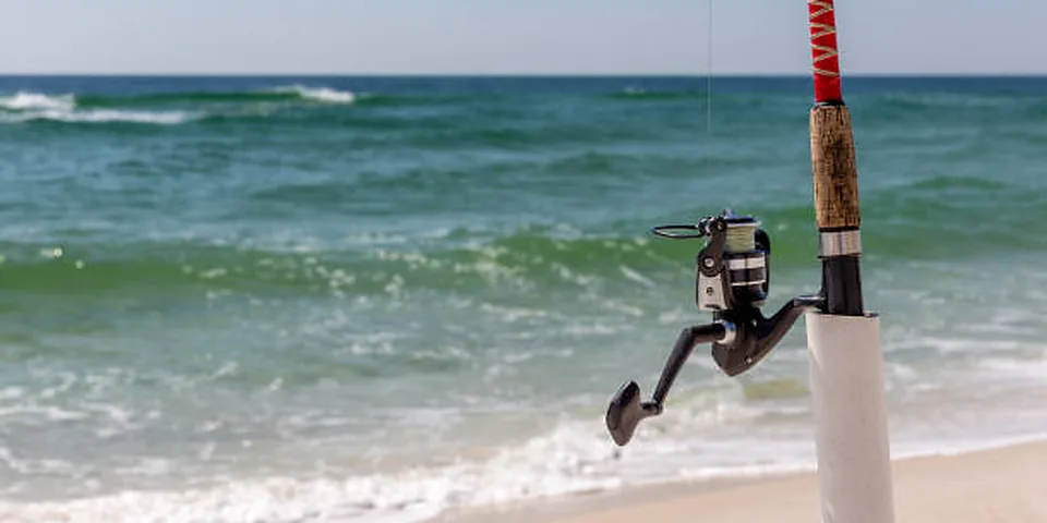 Fishing rod beside quiet coastal water with no people or text