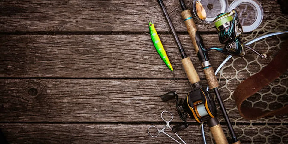 Two different sized fishing rods on an empty dock beside calm water